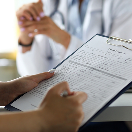 Person filling out dental patient paperwork on a clipboard