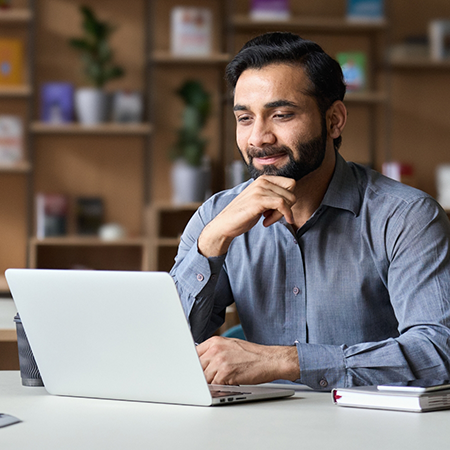 Smiling man sitting at a table using his laptop