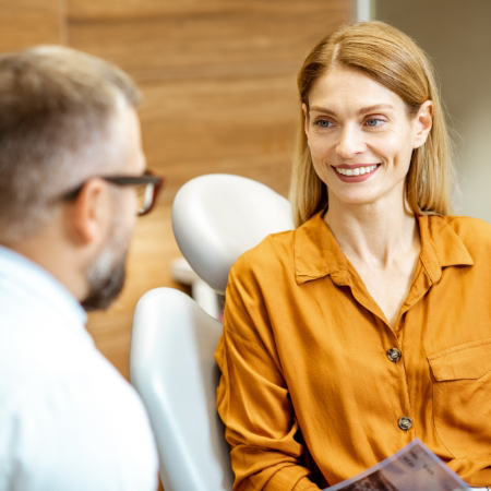 Woman in dental treatment chair smiling at her dentist in Deerfield